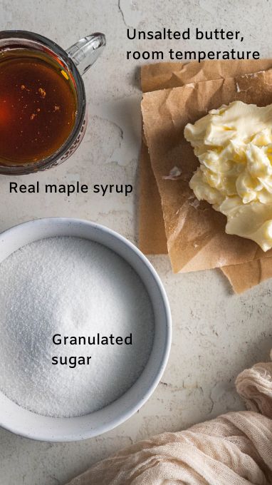 Ingredients for gluten free maple cupcakes. This image shows a measuring cup with maple syrup, the softened butter on parchment paper, and a bowl of granulated sugar.