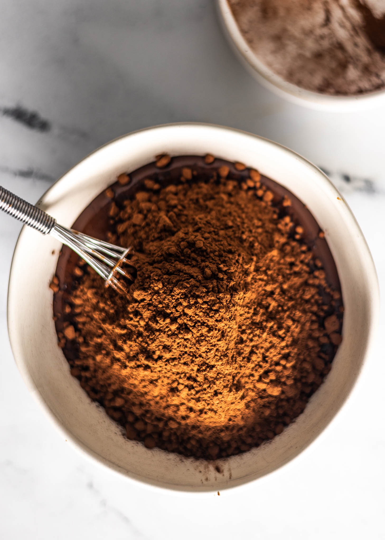 Cocoa powder that has been added to the bowl of melted butter and semi-sweet chocolate chips