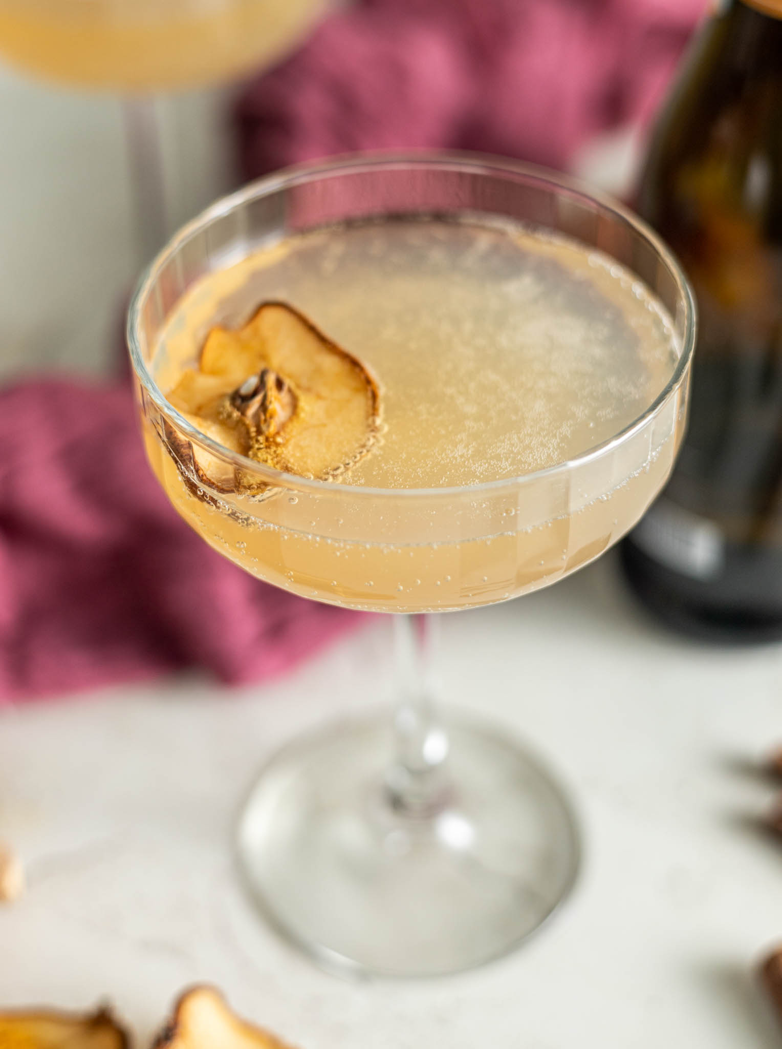 Close up, slightly overhead image of prosecco spritzer. This image shows the finished cocktail with a dried pear slice floating on top.
