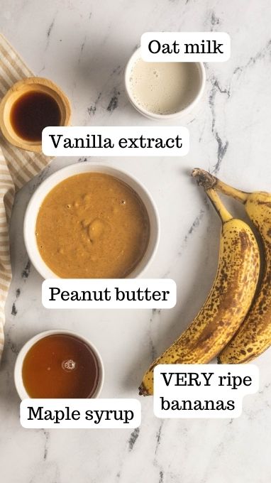 Ingredients for the peanut butter banana oatmeal bars. This image shows bowls with oat milk, vanilla extract, peanut butter, bananas, and maple syrup.