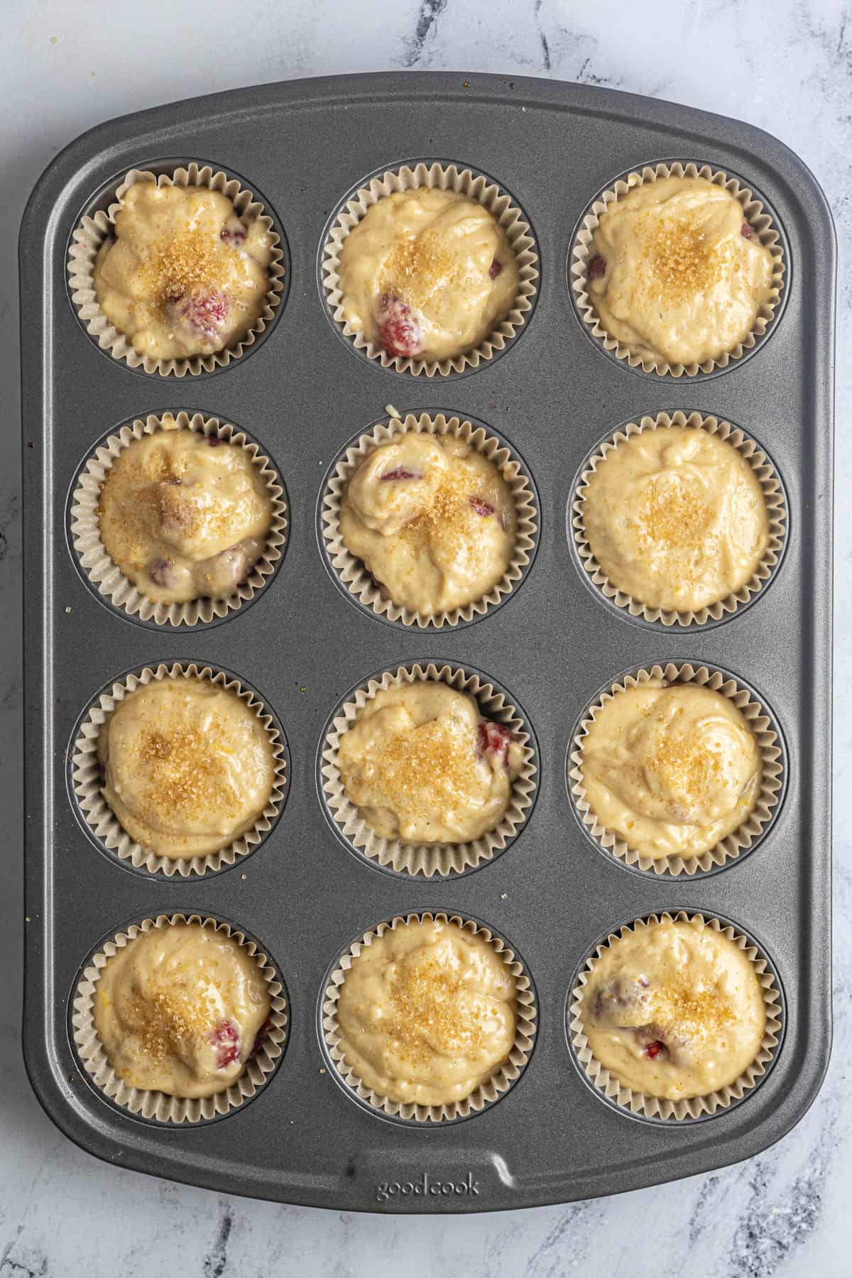 This image shows the muffin batter once it's been divided in the muffin pans. The Gluten Free Raspberry Muffins have been lightly sprinkled with coarse sugar.