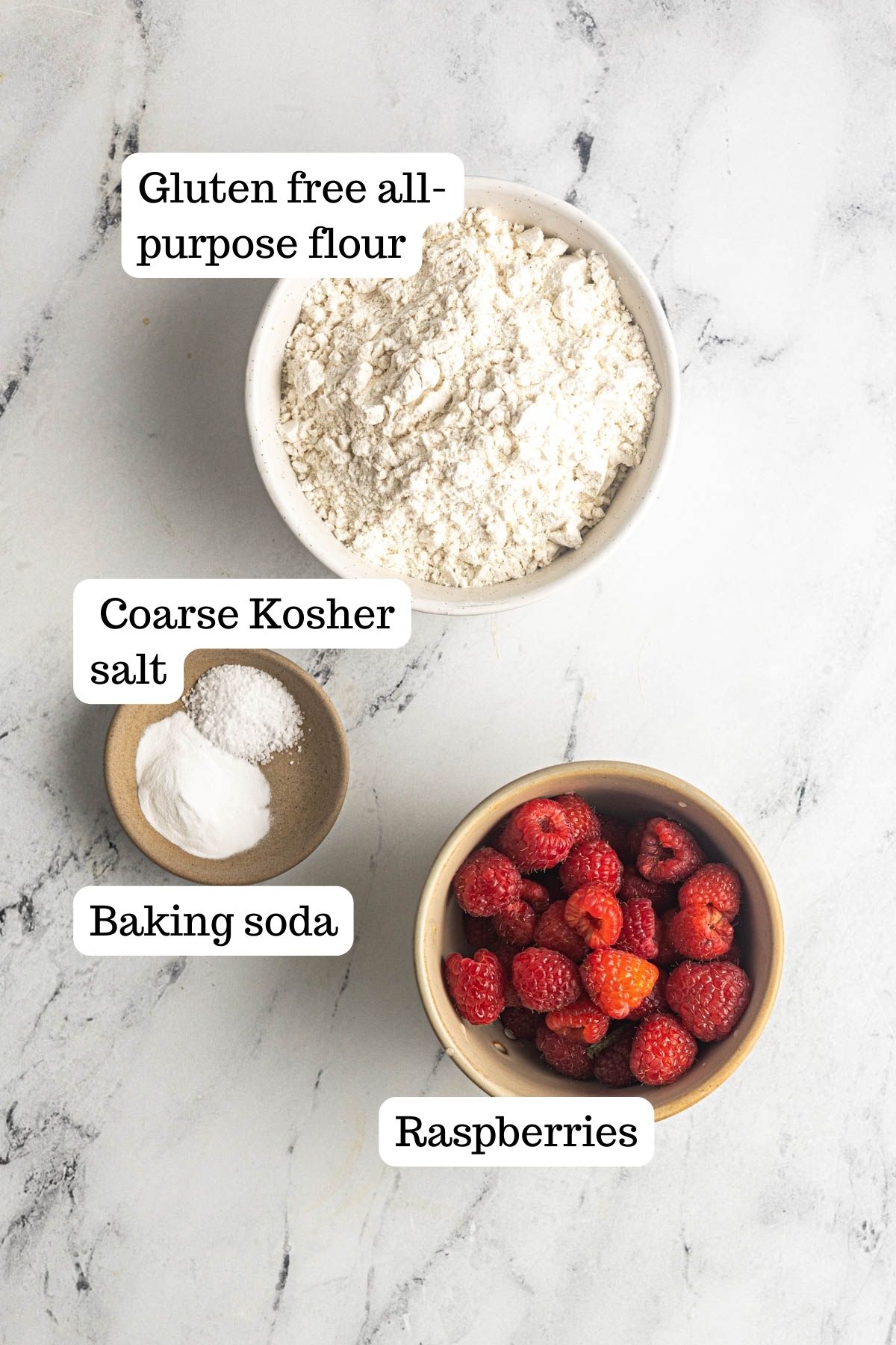 This image shows the dry ingredients for the Gluten Free Raspberry Muffins. The bowls are filled with Gluten free all-purpose flour, coarse Kosher salt, baking soda, and raspberries.