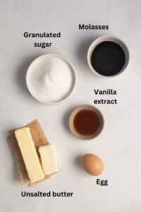 Image showing ingredients for gluten-free gingersnaps. The ingredients shown are granulated sugar, molasses, vanilla extract, butter, and egg.