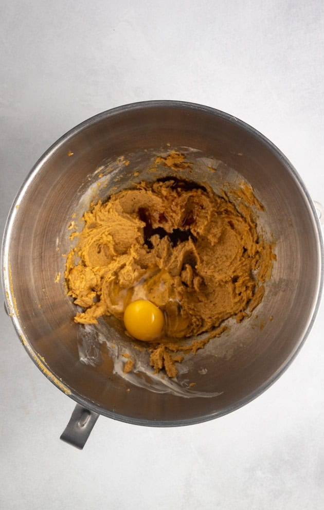 This image shows the process for making gluten-free gingersnaps. This image shows the egg and vanilla being added to the creamed butter and sugar mixture.