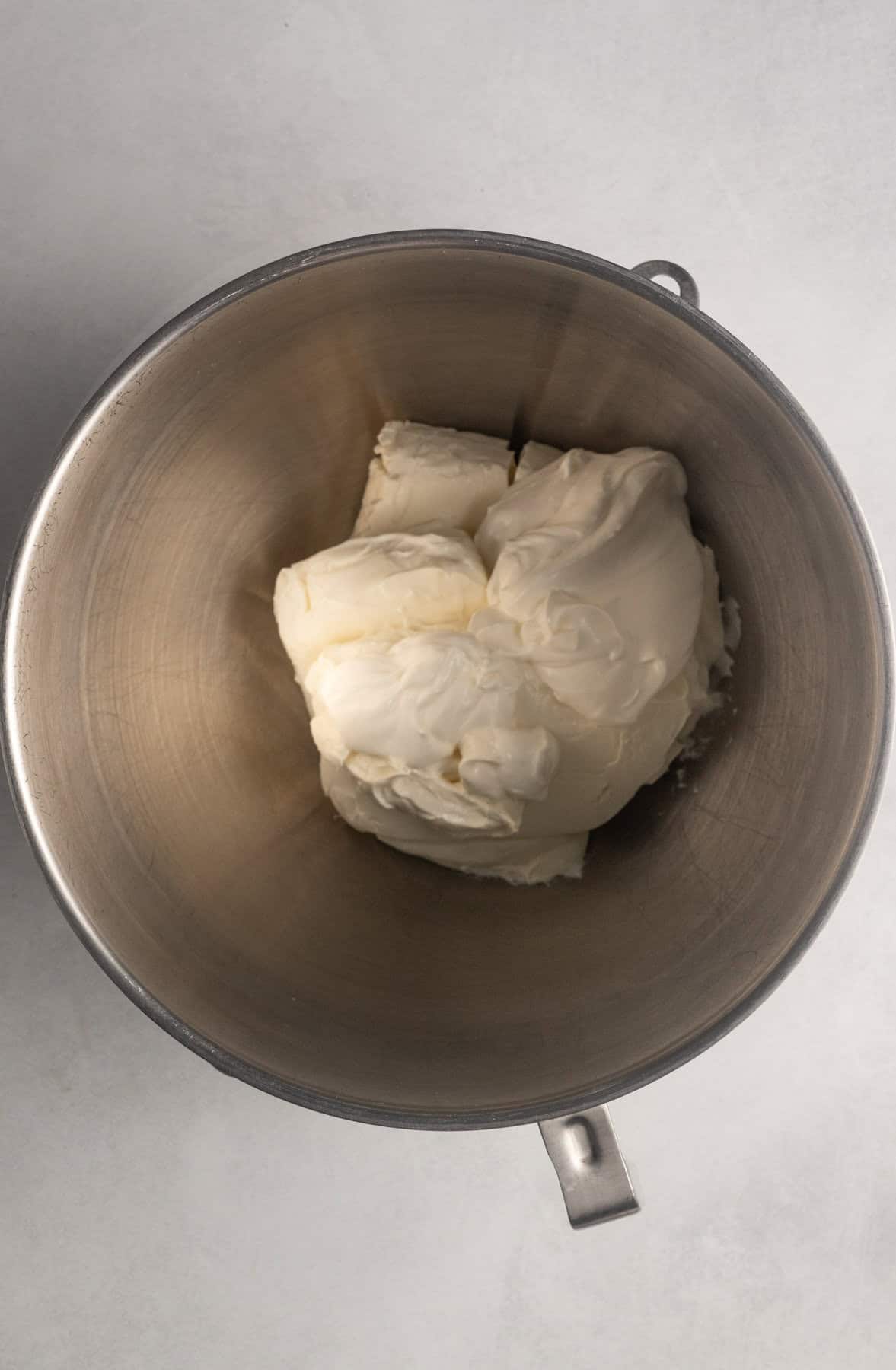 Image shows ingredients for gluten free pumpkin cheesecake filling being added to the mixture. So far, the cream cheese and sour cream have been added.