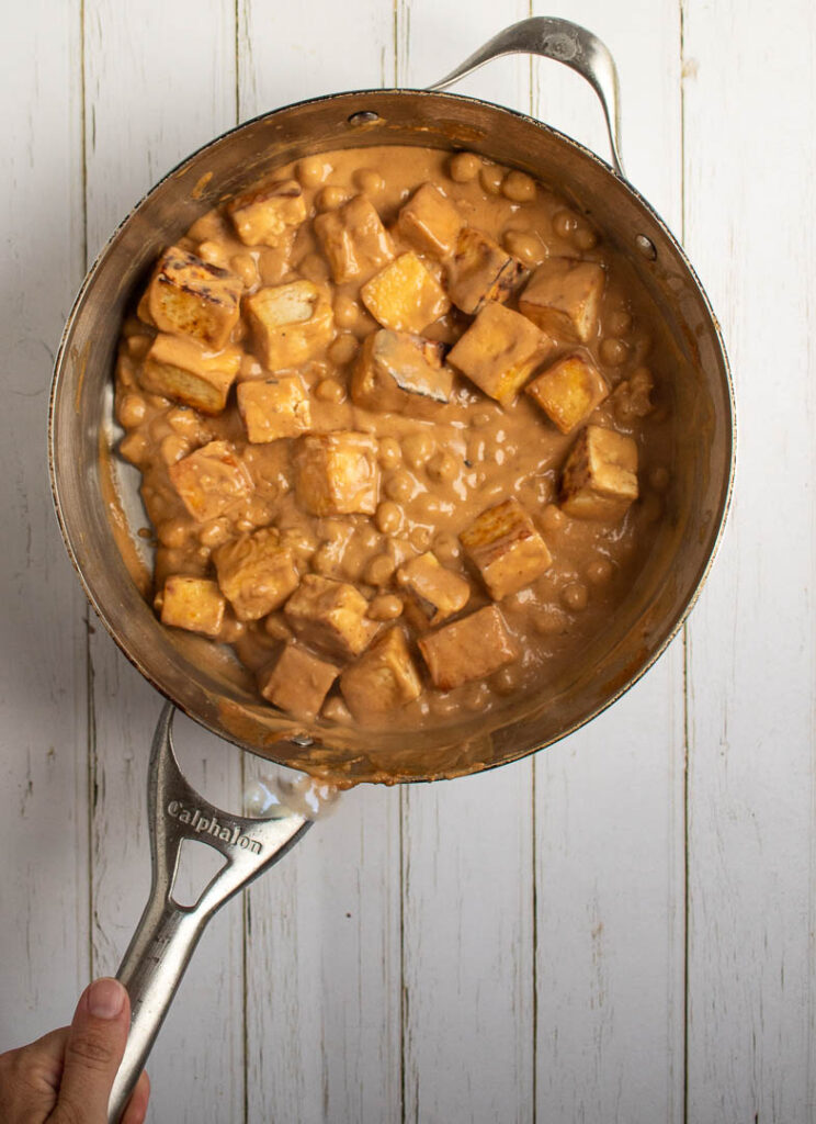 Tofu and chick peas in a pan with peanut sauce.
