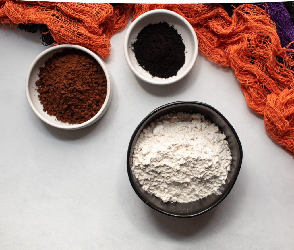 Ingredients in bowls. Dark cocoa powder, black cocoa powder, gluten free all-purpose flour, salt