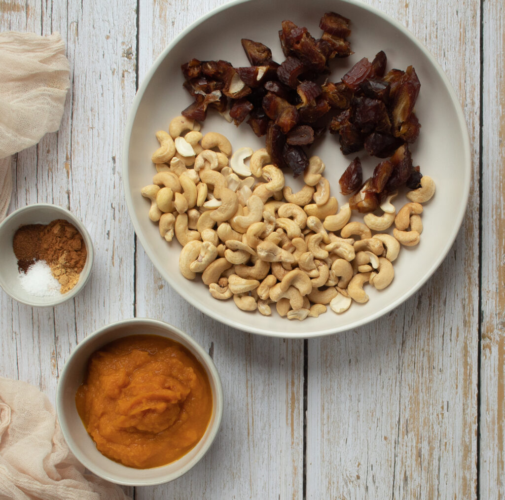 bowls of ingredients with chopped dates, cashews, pumpkin puree, spices and salt